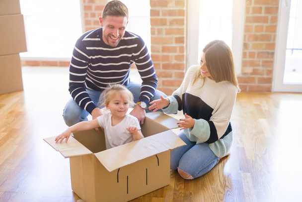 Ребенок, играющий с родителями на картонном ящике в новом доме
 - Фото, изображение