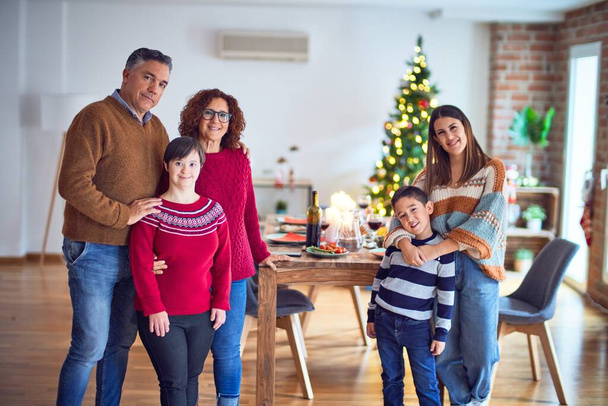 Όμορφη οικογένεια χαμογελά ευτυχισμένη και αυτοπεποίθηση. Στέκονται και ποζάρουν γύρω από το χριστουγεννιάτικο δέντρο στο σπίτι - Φωτογραφία, εικόνα