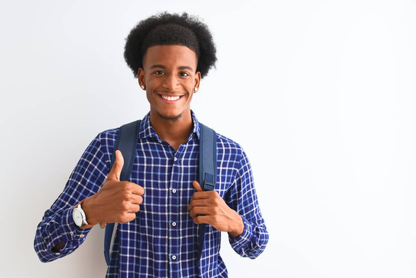 African american tourist man wearing backpack standing over isolated white background happy with big smile doing ok sign, thumb up with fingers, excellent sign - Foto, immagini