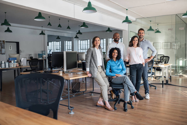 Portrait of a smiling group of diverse businesspeople working together in a modern open plan office - Photo, image