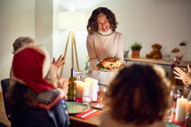 Hermoso grupo de mujeres sonriendo felices y confiadas. Mostrando pavo asado celebrando la Navidad en casa
 - Foto, Imagen
