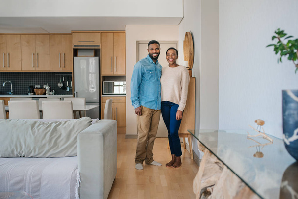 Portrait of a content young African American couple smiling while standing together in their stylish modern apartment - Foto, Bild