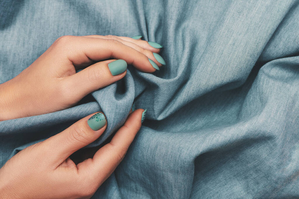 Close up view of woman hands with trendy manicure on jeans cloth background. - Photo, image