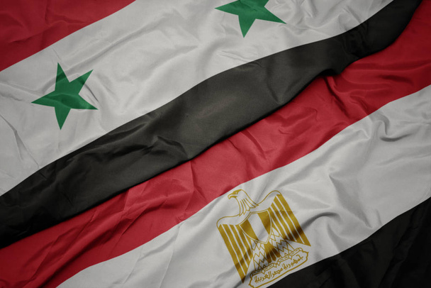 размахивая красочным флагом Египта и национальным флагом Сирии
. - Фото, изображение