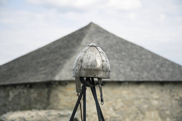 Сталевий шолом середньовічний мир лицарського обладунку на поліцейському з розмитим неорієнтованим дахом замкової вежі в м'яких кольорах, копіювання простору
 - Фото, зображення