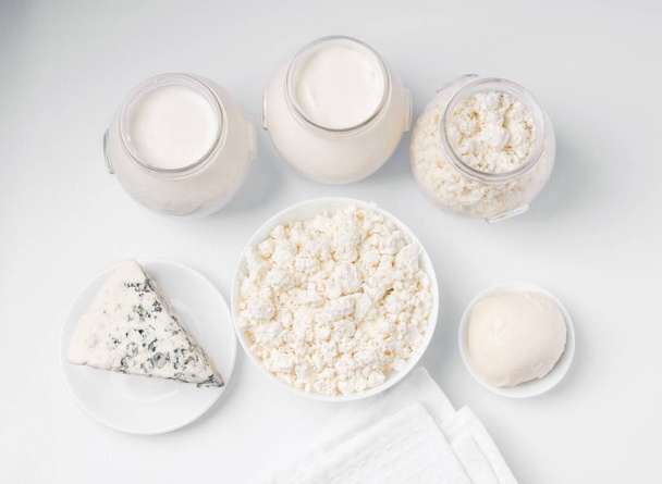 γαλακτοκομικά προϊόντα σε λευκό φόντο. Μπλε τυρί, μοτσαρέλα, τυρί cottage, γάλα, ξινή κρέμα, προζύμι. λευκό ύφασμα - Φωτογραφία, εικόνα