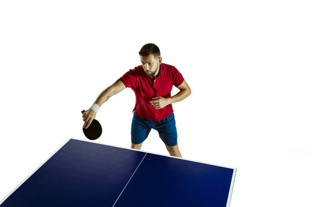 Mladý muž hraje stolní tenis na bílém pozadí studia - Fotografie, Obrázek