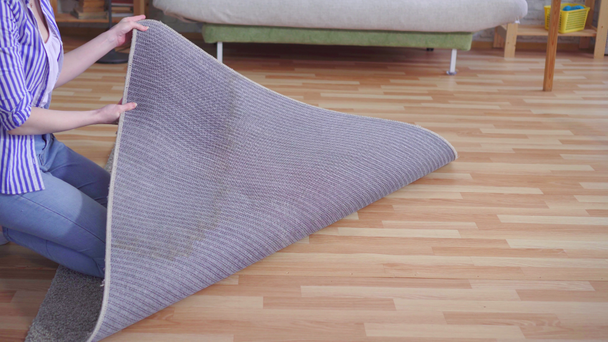 mujer joven examina una mancha húmeda en la alfombra
 - Imágenes, Vídeo