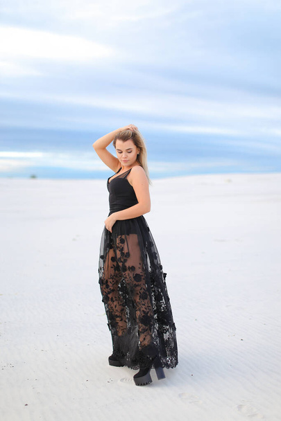 Молодая красивая девушка в черном прозрачном платье и ходьба в зимней степи
. - Фото, изображение