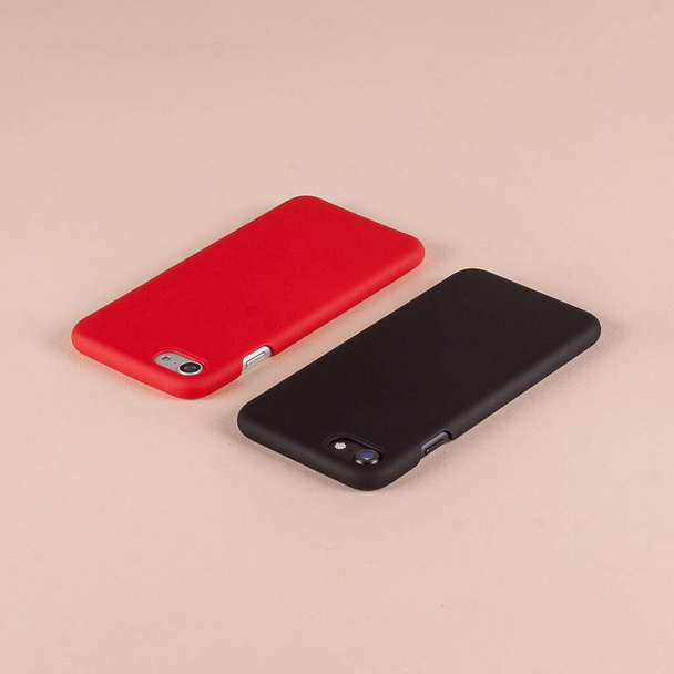 Black and red cell phones in case on pink background - Foto, Imagen