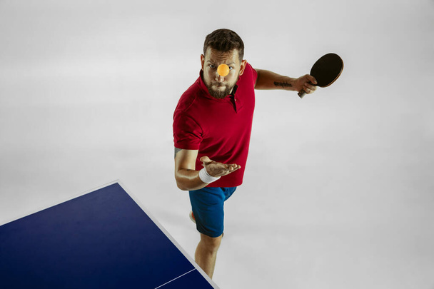 junger Mann spielt Tischtennis auf weißem Studiohintergrund - Foto, Bild