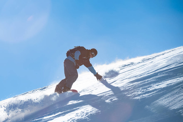 Snowboarder Riding Red Snowboard in Mountains at Sunny Day. Snowboarding and Winter Sports - Photo, Image