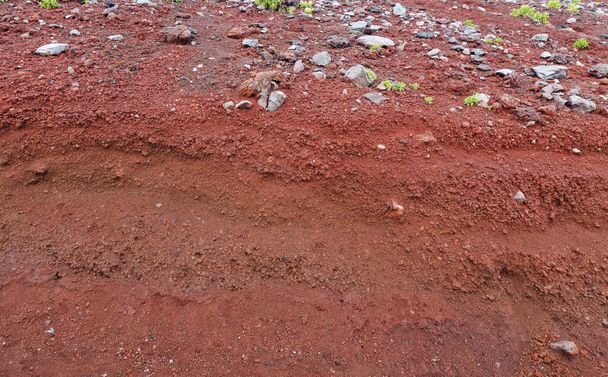 Un corte de tierra con rocas y tierra roja
 - Foto, Imagen