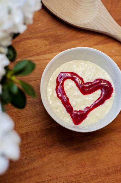 Smaczny i pyszny pudding ryżowy z czerwonym malinowym sercem pośrodku, na drewnianej desce do krojenia. Tradycyjny świąteczny deser w Finlandii - Zdjęcie, obraz