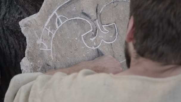 Stone carving process. Stone sculptor or stonecutter creates pattern on the stone. Craftsman cuts an ornament on a rock slab using a hand engraver. The sculptor carves a pattern on a stone slab with a - Footage, Video