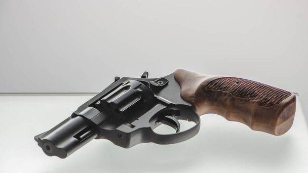 black revolver with wooden handle on glass table - Photo, Image