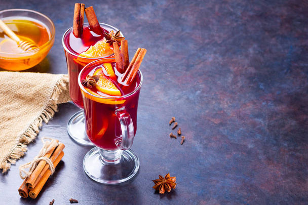 Red mulled wine on burlap. Mulled wine with oranges, cinnamon and cloves on a dark background. Hot wine with spices - Foto, Imagen