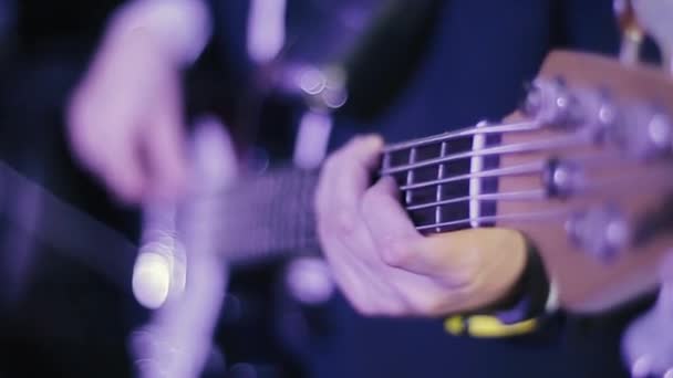プロの若いベース奏者がギターソロで演奏する。ベースギターとロックギタリストの手を間近で見ることができます。音楽家はコンサートで演奏し、楽器を上手に演奏する. - 映像、動画