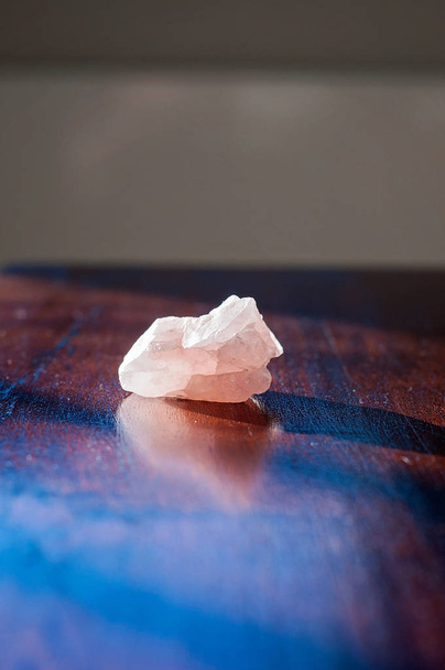 Şifalı gül kristali ya da ahşap bir masada değerli bir taş. Güzel pembe bir aşk taşı güzel titreşimler ve olumlu titreşimler getirir. - Fotoğraf, Görsel