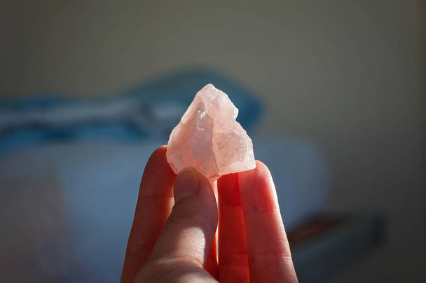 Sostener un cristal de rosa curativo o una piedra preciosa. Una hermosa piedra de amor rosa aislada trae buenas vibraciones y vibraciones positivas
 - Foto, Imagen