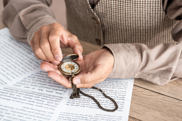 Ausgeschnittene Ansicht eines Rentners mit Taschenuhr in der Nähe von Papieren mit Briefen  - Foto, Bild