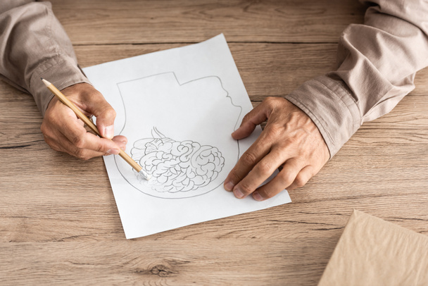 Ausgeschnittener Blick auf Rentner mit Alzheimer-Krankheit zeichnet menschlichen Kopf und Gehirn  - Foto, Bild