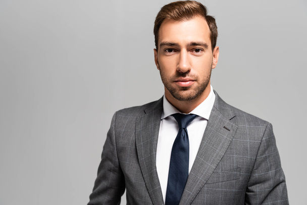 handsome businessman in suit looking at camera isolated on grey  - Photo, image