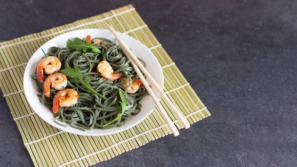 Soba spirulina noodles με γαρίδες σε λευκό πιάτο. Ασιατική δημιουργική έννοια τροφίμων. - Φωτογραφία, εικόνα