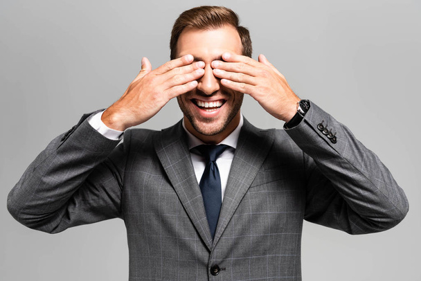 smiling businessman in suit obscuring face isolated on grey  - Photo, Image