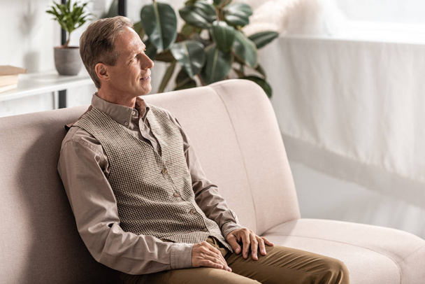 cheerful retired man sitting on sofa at home  - Photo, Image