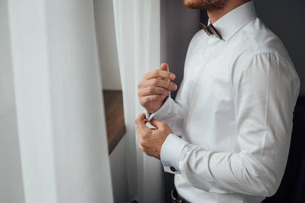 Man buttons cuff link on cuffs sleeves luxury white shirt. - Fotó, kép
