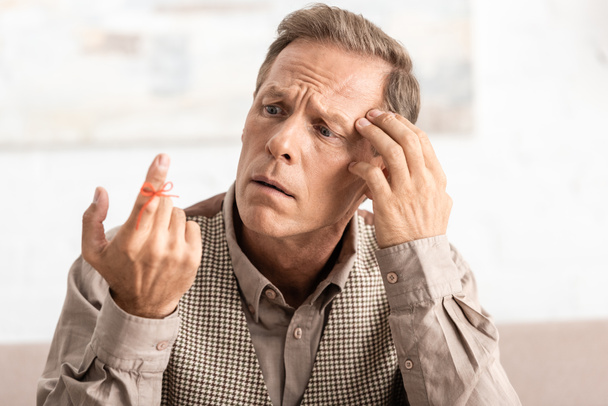 foco seletivo de homem aposentado confuso olhando alzheimers doença corda lembrete dedo humano
  - Foto, Imagem