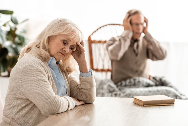 selective focus of upset retired woman sitting near husband with mental illness  - Foto, afbeelding