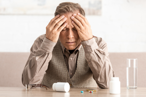 sick retired man with alzheimer disease near pills and bottles on table  - 写真・画像