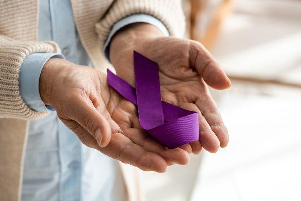 cropped view of senior woman holding purple ribbon at home  - Photo, Image