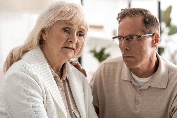 disgustada hombre mayor en gafas mirando enfermo esposa con alzheimer
  - Foto, Imagen