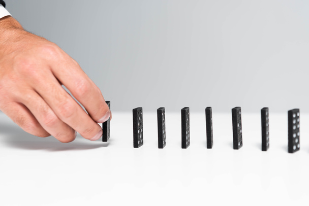 przycięty widok człowieka zbieranie domino z rzędu izolowane na szary  - Zdjęcie, obraz
