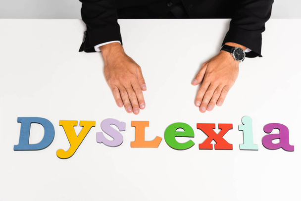 oříznutý pohled na obchodníka v obleku sedícího poblíž nápisu dyslexie  - Fotografie, Obrázek
