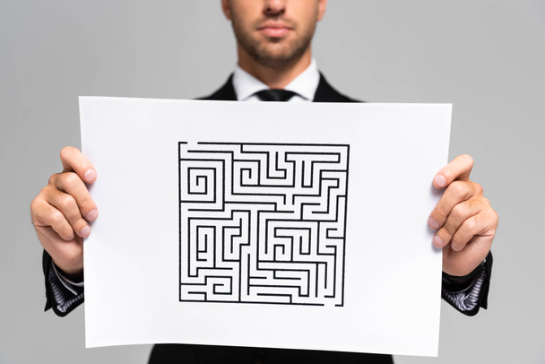 vue recadrée d'un homme d'affaires tenant du papier avec labyrinthe isolé sur gris
  - Photo, image