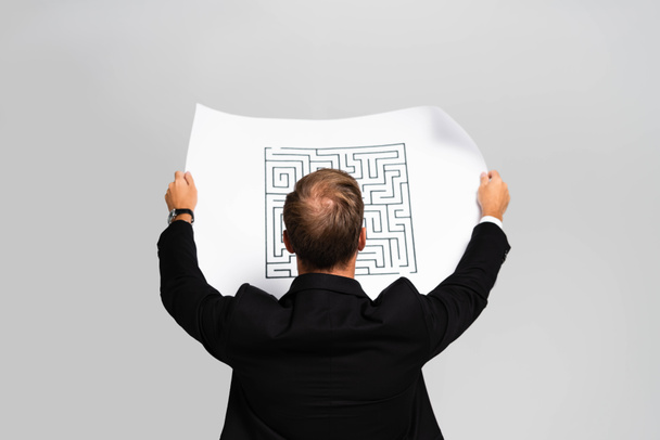 takaisin näkymä liikemies puku katsomalla paperia labyrintti eristetty harmaa
  - Valokuva, kuva