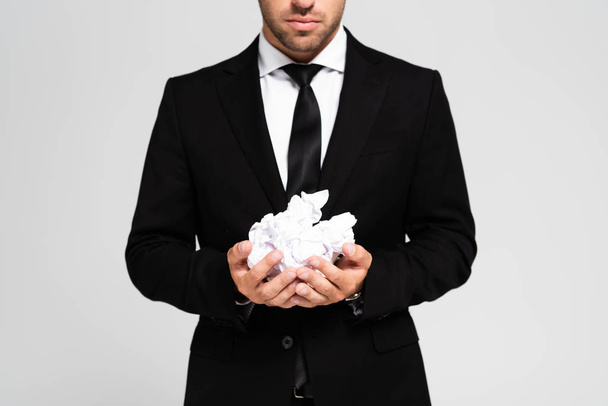 bijgesneden beeld van zakenman in pak met verkreukelde papieren geïsoleerd op grijs - Foto, afbeelding