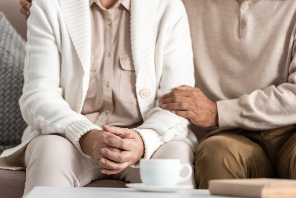 cropped view of senior man and woman sitting on sofa  - Photo, Image