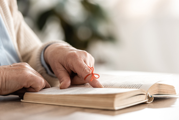 Alzheimer hastası yaşlı bir kadın insan parmağını kitabın yanına koyuyor. - Fotoğraf, Görsel