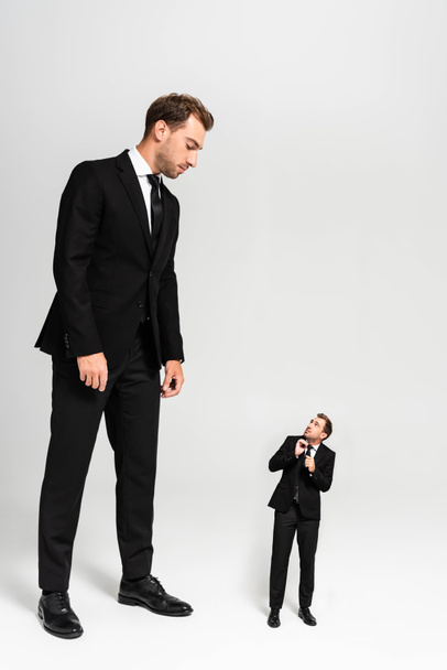 hombre de negocios en traje mirando marioneta asustada sobre fondo gris
  - Foto, Imagen