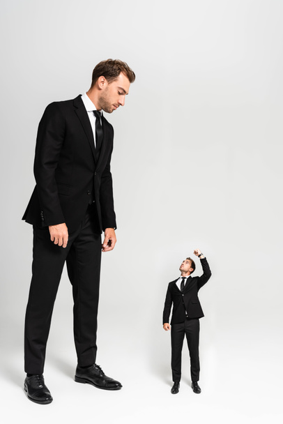 hombre de negocios en traje mirando marioneta mostrando puño sobre fondo gris
  - Foto, Imagen