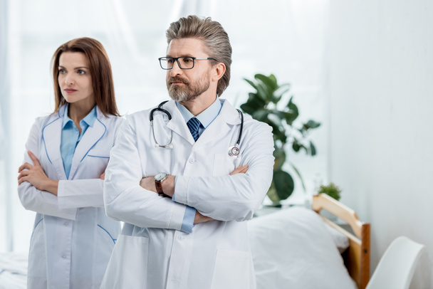 médicos con batas blancas con brazos cruzados mirando hacia otro lado en el hospital
  - Foto, imagen