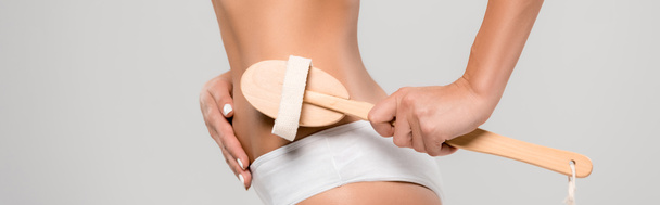 cropped view of slim woman in underwear massaging body with wooden massage brush isolated on grey, panoramic shot - Fotoğraf, Görsel