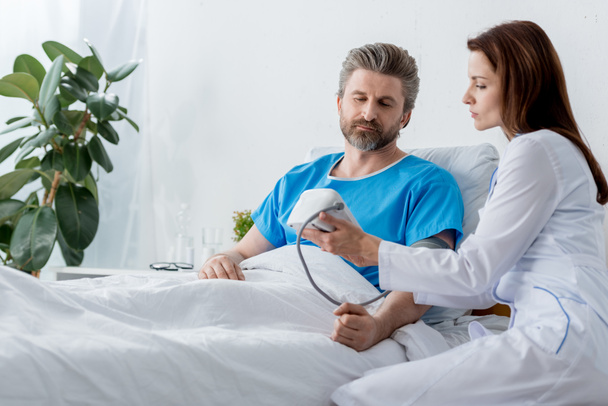 orvos fehér köpenyben méri a beteg vérnyomását a kórházban  - Fotó, kép
