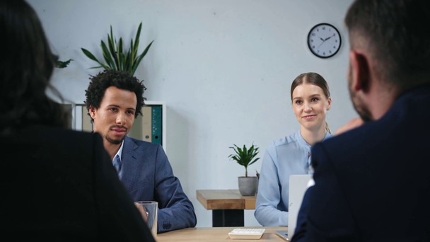 positive multicultural businesspeople talking to colleagues during meeting - Footage, Video