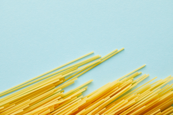 top view of raw spaghetti on blue background with copy space - Fotó, kép